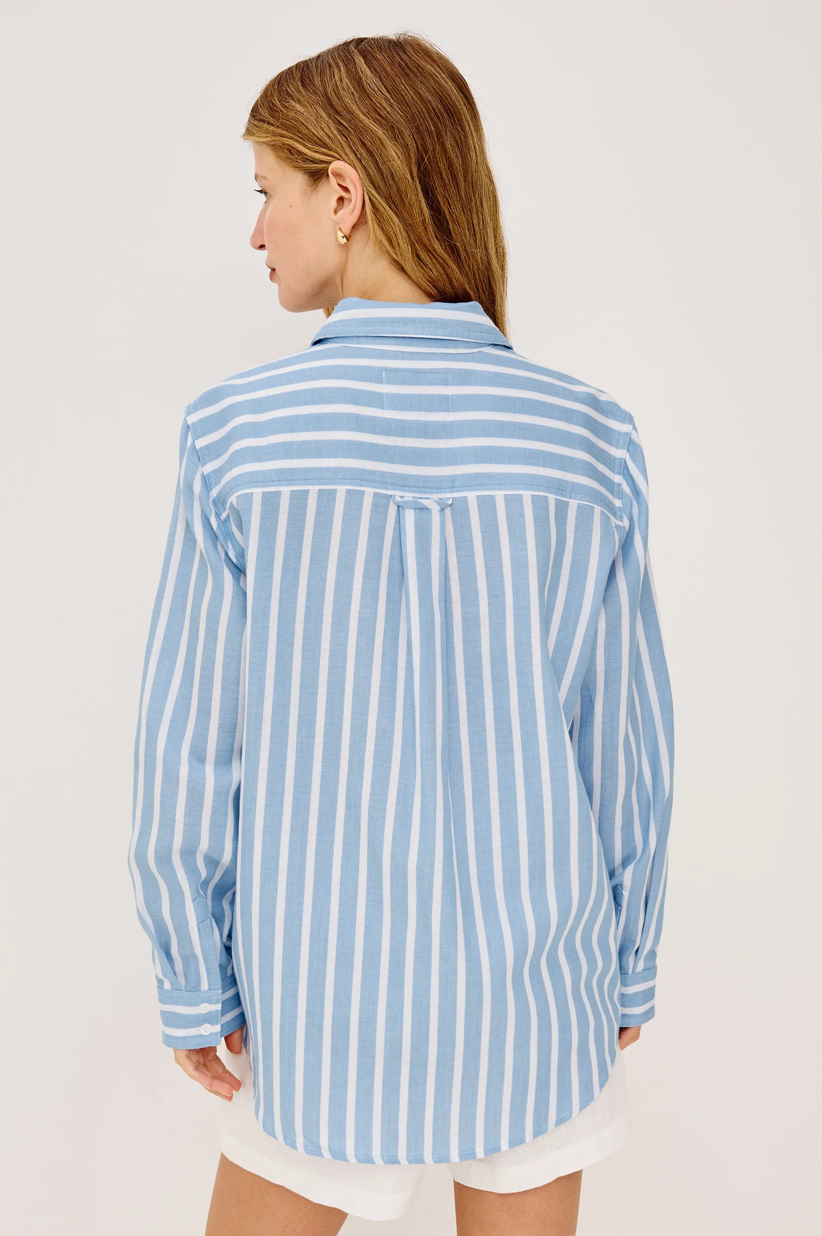 Woman wearing a blue and white Rails shirt striped shirt against a plain background rear view