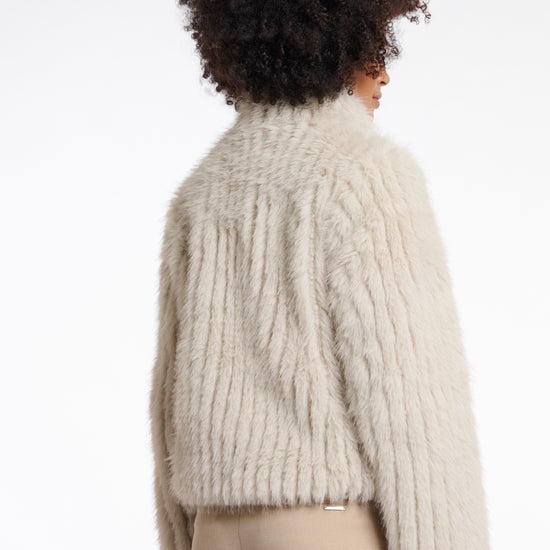 beige faux fur jacket with high neck, central closure and stripe detailing in the fur rear view 