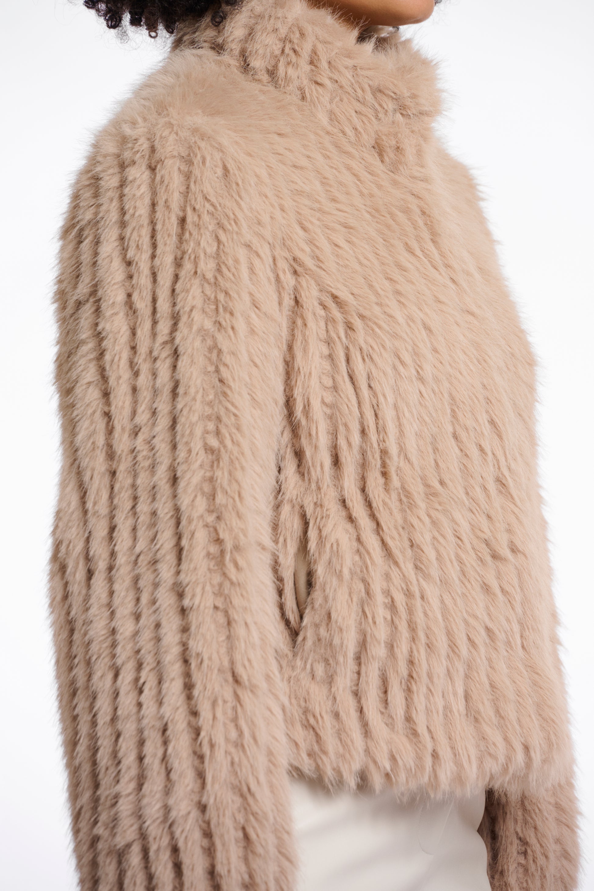 light beige faux fur jacket with high neck, central closure and stripe detailing in the fur side view 