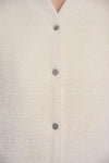 Close-up of a cream-colored fuzzy cardigan with dark gray buttons, showing the soft texture and collar.