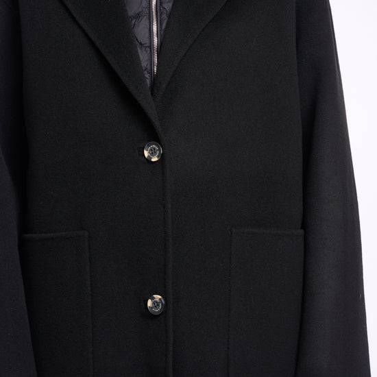 single breasted black coat with interior quilted gilet and 2 patch pockets close up