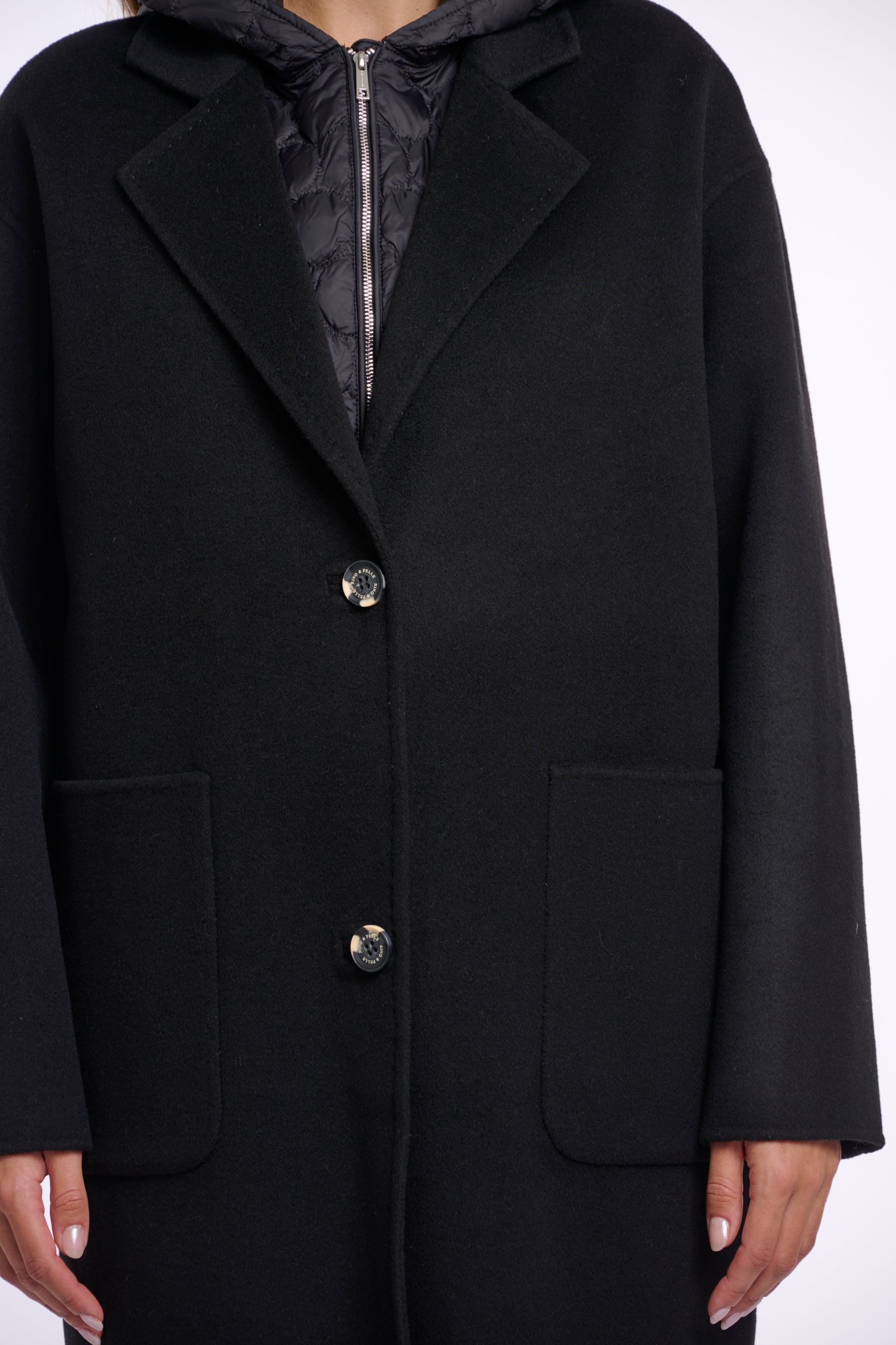 single breasted black coat with interior quilted gilet and 2 patch pockets close up