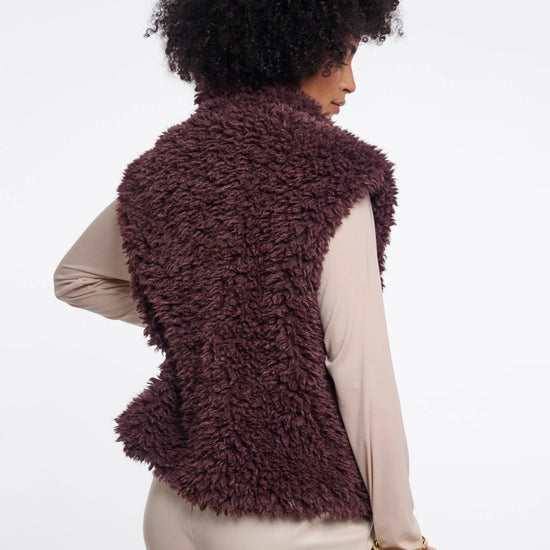 Person wearing a fluffy brown vest on a white background