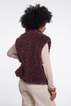 Person wearing a fluffy brown vest on a white background