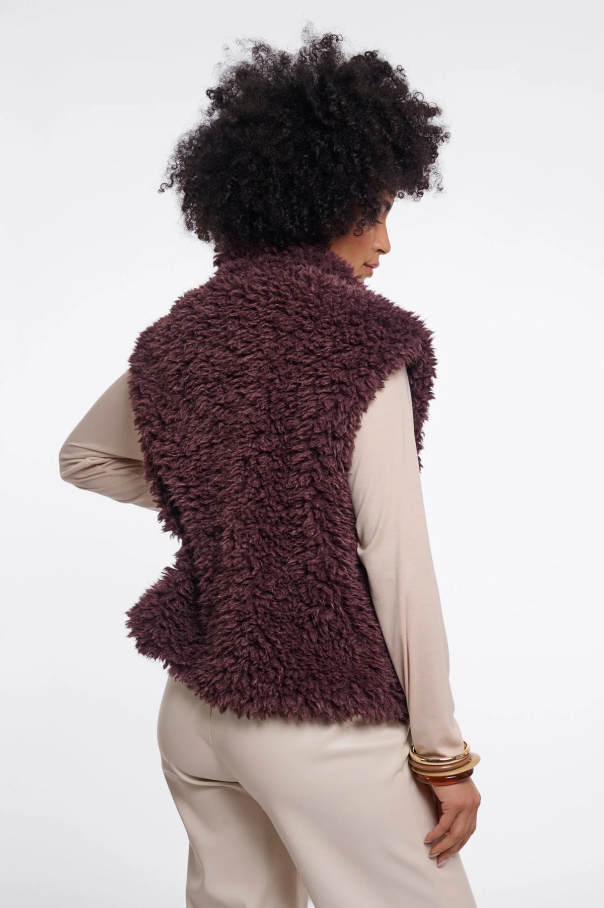 Person wearing a fluffy brown vest on a white background