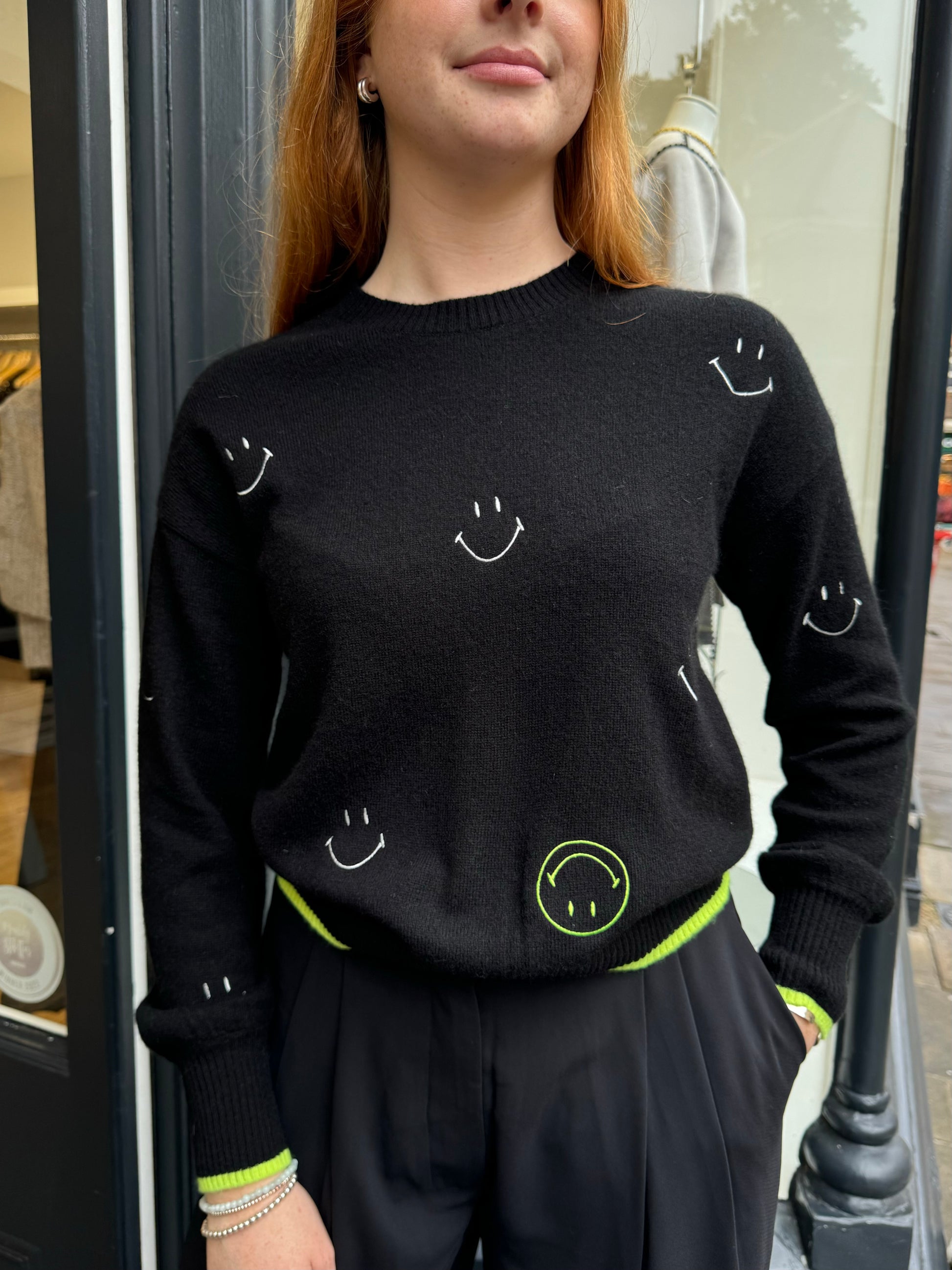 Cashmere black round neck jumper with white and neon green embroidery smiley faces. 