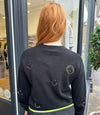 Cashmere black round neck jumper with white and neon green embroidery smiley faces. 