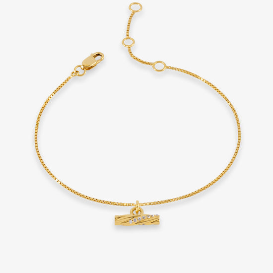 A delicate gold chain bracelet with a small horizontal bar charm displayed on a clean white background.