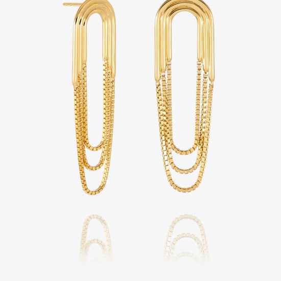 A pair of gold paperclip-shaped drop earrings with layered chain details, displayed on a clean white background with a soft reflection below.
