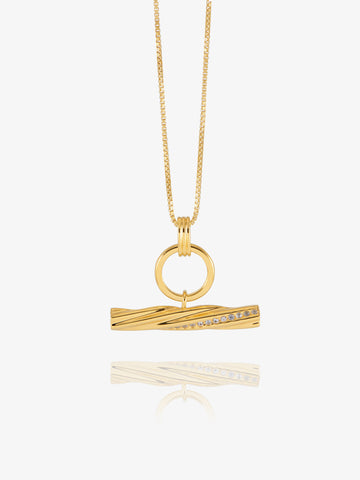 A gold pendant necklace featuring a twisted bar design with a row of small clear stones, suspended from a delicate gold chain against a light gray background.