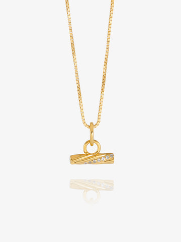 A gold chain necklace with a small horizontal bar pendant featuring a row of clear stones, displayed against a light gray background with a soft reflection below.
