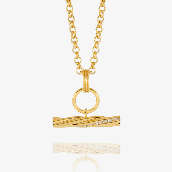 A gold chain necklace with a twisted bar pendant featuring a row of small clear stones, displayed on a clean white background with a soft reflection below.