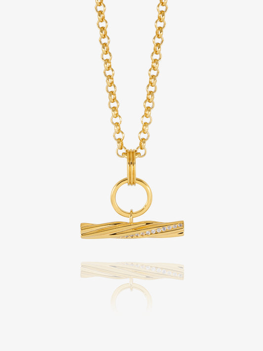 A gold chain necklace with a twisted bar pendant featuring a row of small clear stones, displayed on a clean white background with a soft reflection below.