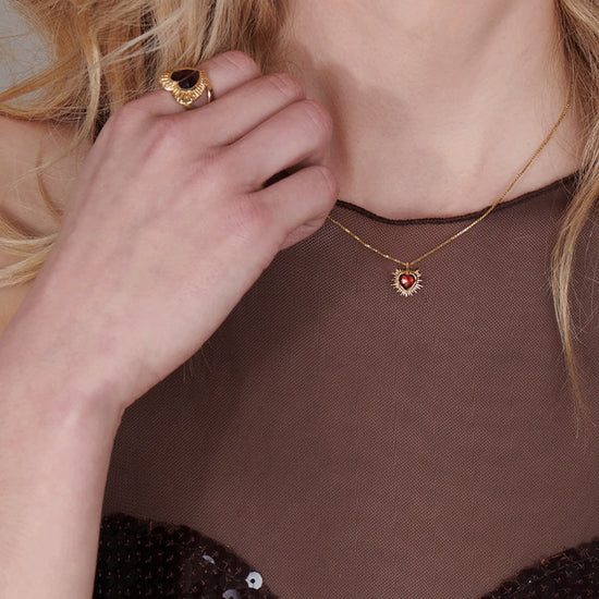 gold spiky heart with red stone inside on a gold chain from rachel jackson model shot