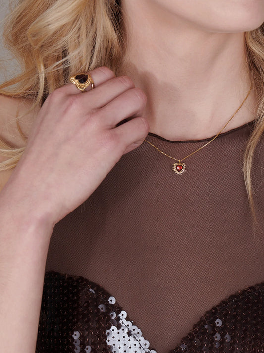gold spiky heart with red stone inside on a gold chain from rachel jackson model shot