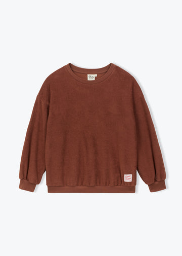 A brown long-sleeve crewneck sweatshirt with a small pink brand tag on the lower right hem, displayed flat against a light gray background.