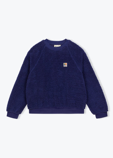 A dark blue sherpa fleece crewneck sweatshirt with a small Carhartt logo patch on the left chest, displayed flat against a light gray background.