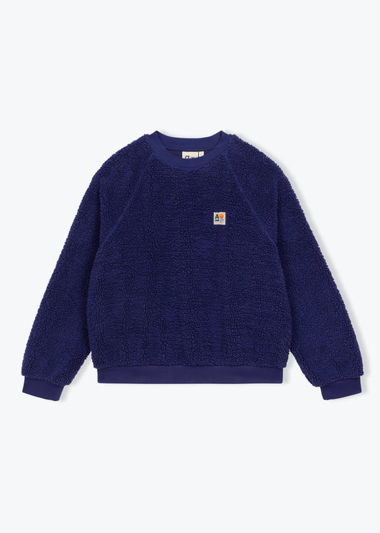 A dark blue sherpa fleece crewneck sweatshirt with a small Carhartt logo patch on the left chest, displayed flat against a light gray background.