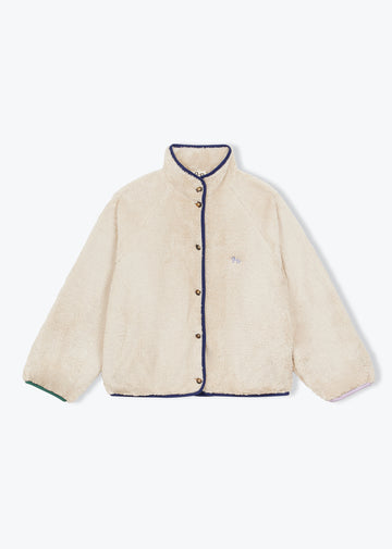 A cream-colored sherpa jacket with dark navy blue trim along the collar, front buttons, cuffs, and hem, featuring a small embroidered logo on the left chest.
