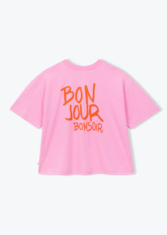 A pink short-sleeve t-shirt with orange text on the back reading 'BON JOUR BONSOIR', displayed against a clean white background.