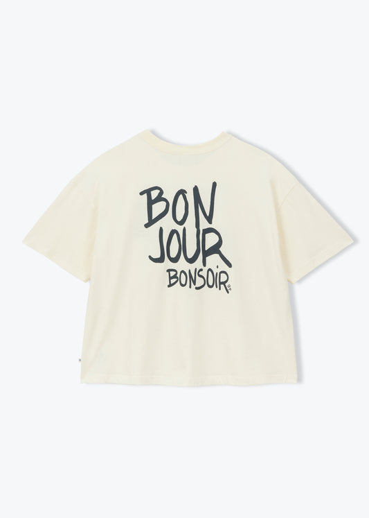 An off-white short-sleeve t-shirt with 'BON JOUR BONSOIR' printed in black across the back, displayed on a clean white background.
