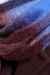 A close-up of a soft, fuzzy scarf or fabric with layered plaid stripes in blue, burgundy, and dark brown.