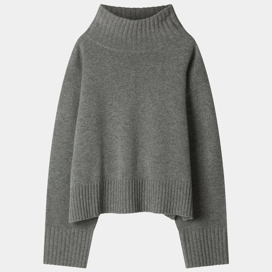 A dark gray knit turtleneck sweater with a relaxed, oversized fit, ribbed collar, cuffs, and hem, displayed against a light gray background.
