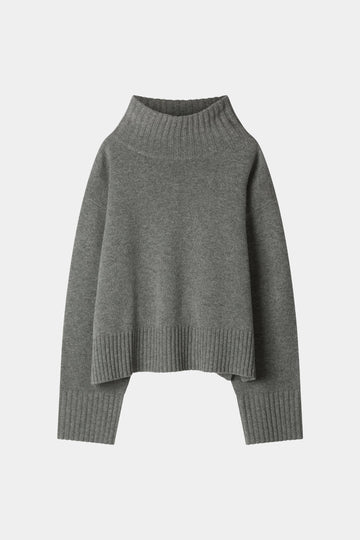 A dark gray knit turtleneck sweater with a relaxed, oversized fit, ribbed collar, cuffs, and hem, displayed against a light gray background.
