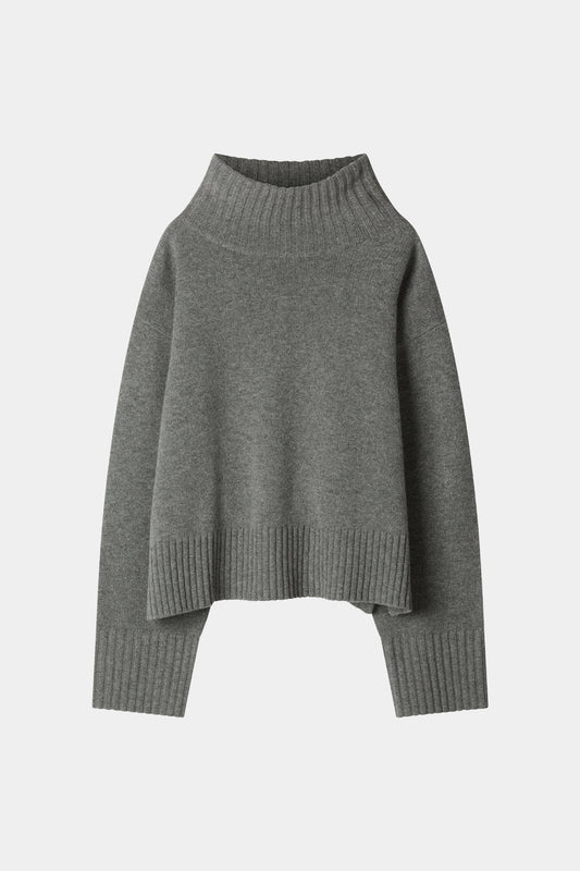 A dark gray knit turtleneck sweater with a relaxed, oversized fit, ribbed collar, cuffs, and hem, displayed against a light gray background.