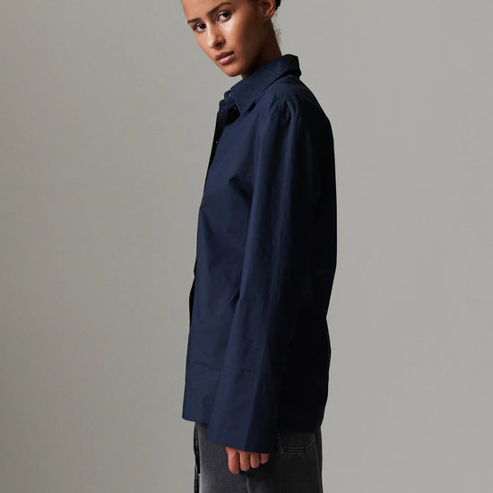 Person wearing a navy blue shirt against a gray background