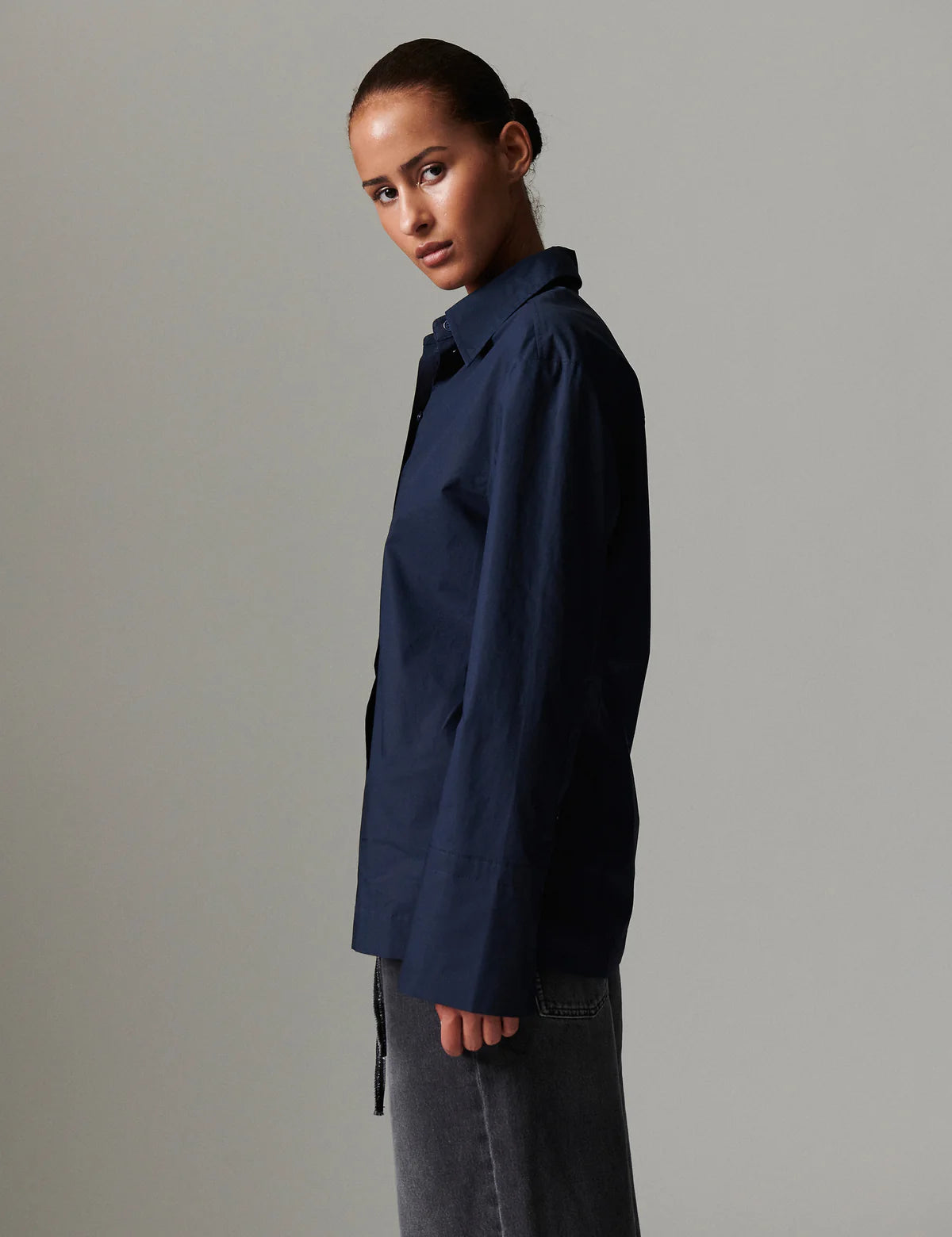 Person wearing a navy blue shirt against a gray background