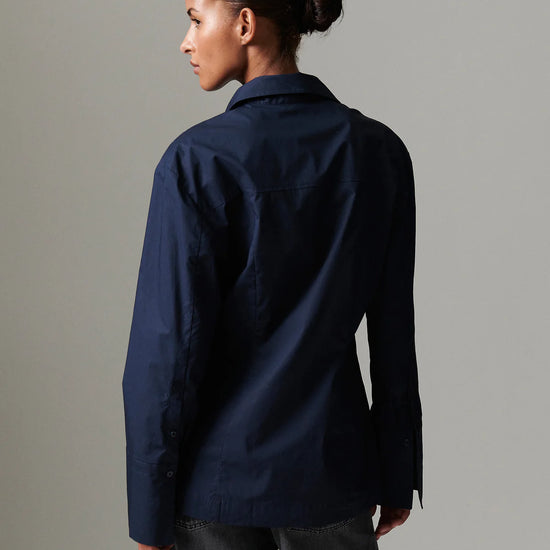 Person wearing a navy blue shirt against a gray background