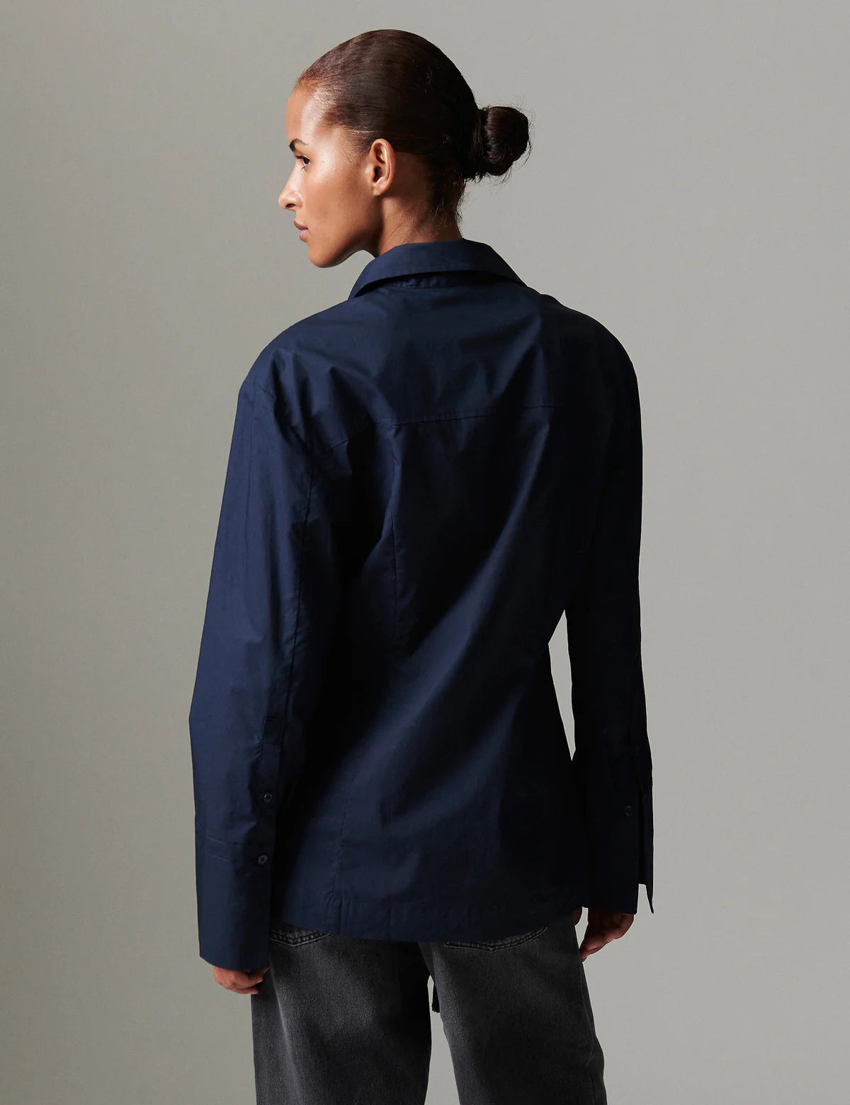 Person wearing a navy blue shirt against a gray background