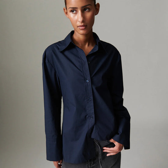 Person wearing a navy blue shirt against a plain background