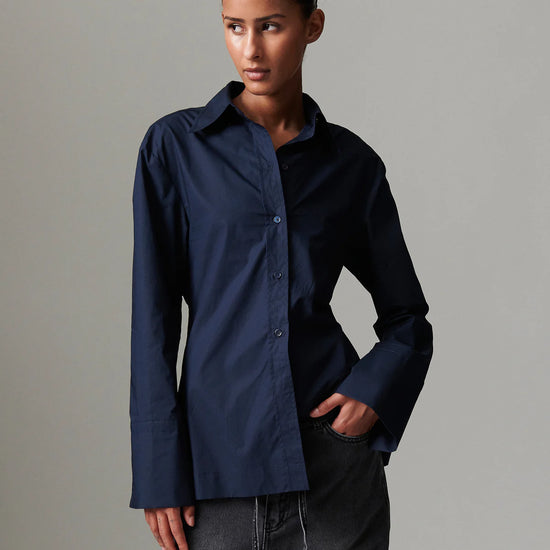 Person wearing a navy blue shirt against a gray background