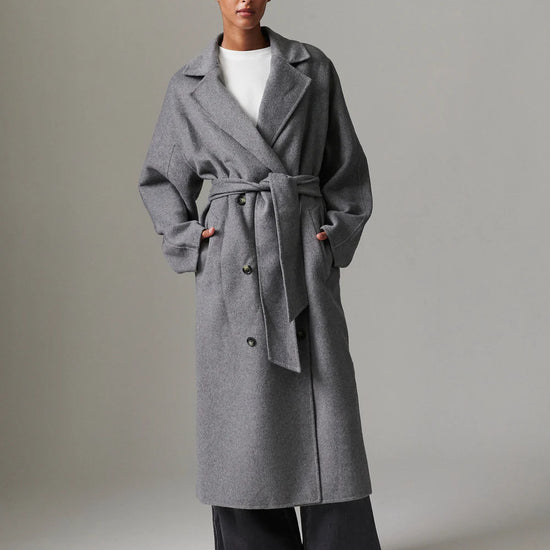 Woman wearing a gray coat with a plain background