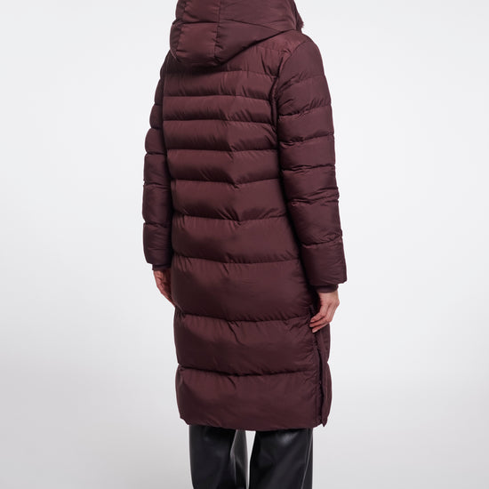 Person wearing a long burgundy puffer coat on a white background