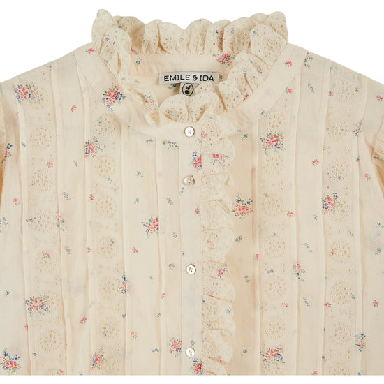 frill stand neck short sleeve pleated button down cream blouse with small floral print throughout from emile and ida close up