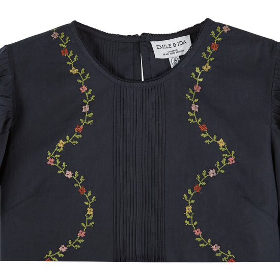 black blouse with flower embroidery on white background close up 