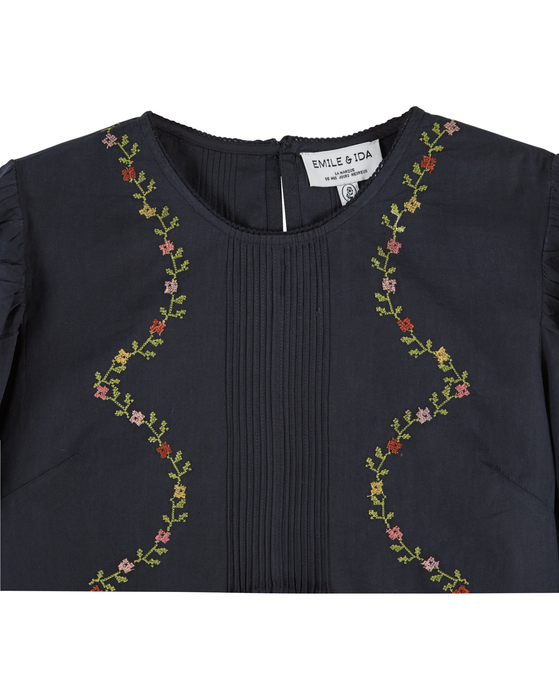 black blouse with flower embroidery on white background close up 