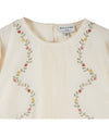 cream blouse with flower embroidery on white background close up of front