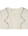 cream blouse with flower embroidery on white background close up of rear view