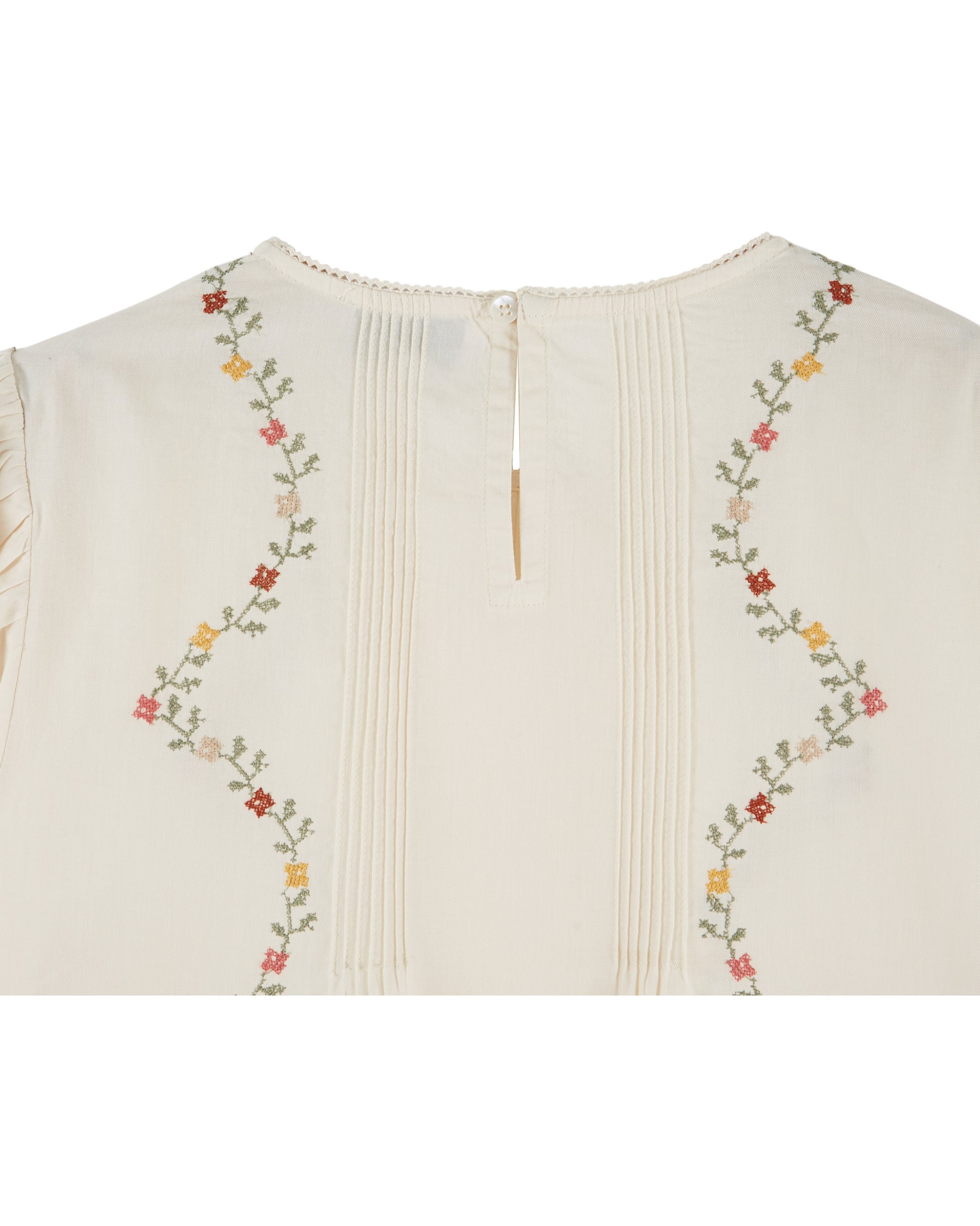 cream blouse with flower embroidery on white background close up of rear view