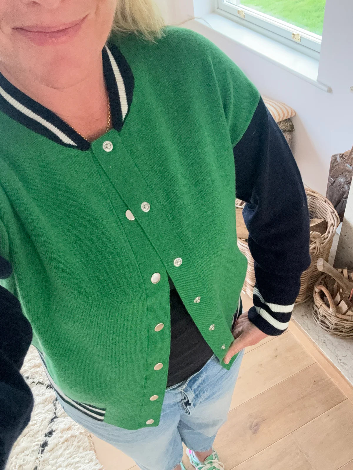 Knitted green bomber jacket with navy sleeves and white details with silver popper closures