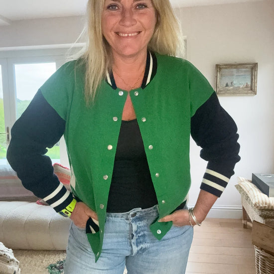 Knitted green bomber jacket with navy sleeves and white details with silver popper closures