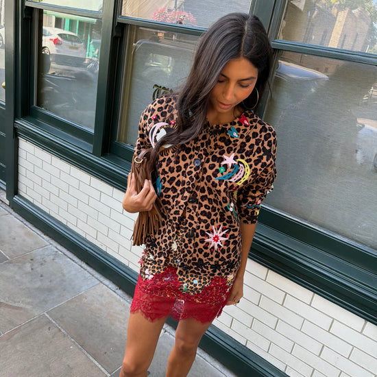 Woman wearing leopard print skirt and skirt with brightly coloured patches on them