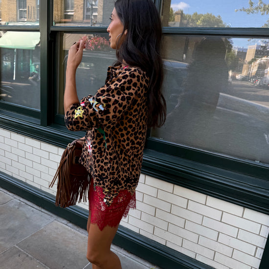 Woman wearing leopard print skirt and skirt with brightly coloured patches on them