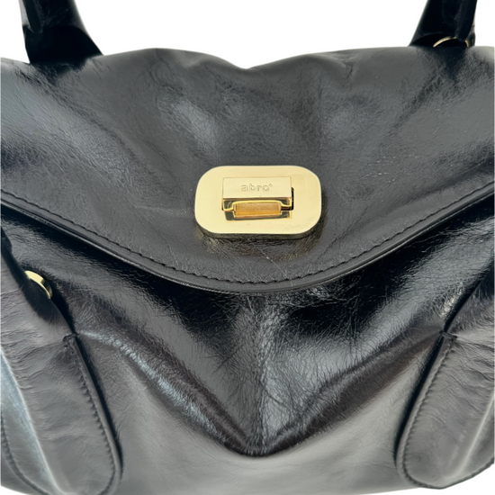 Black shiny leather handbag with shoulder straps and gold buckle detailing.