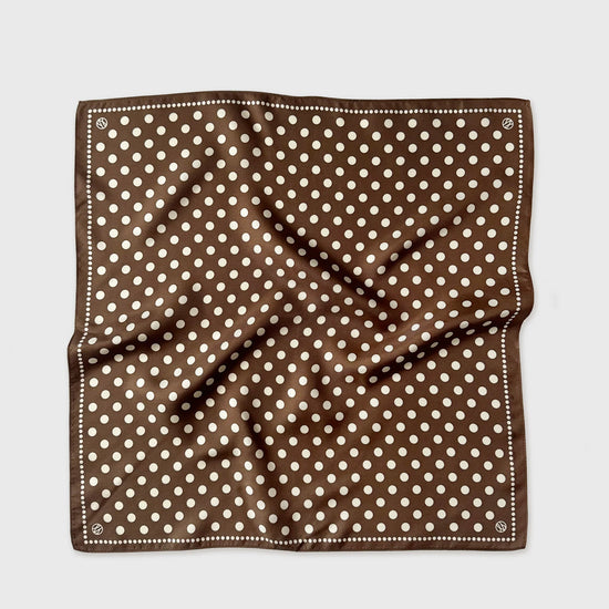 Brown pocket square with white polka dots on a light gray background