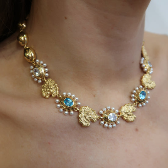 Gold necklace with pearls and blue stones on models neck